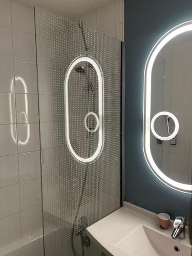 a bathroom with a shower and a sink and a mirror at ibis Cambrai in Cambrai