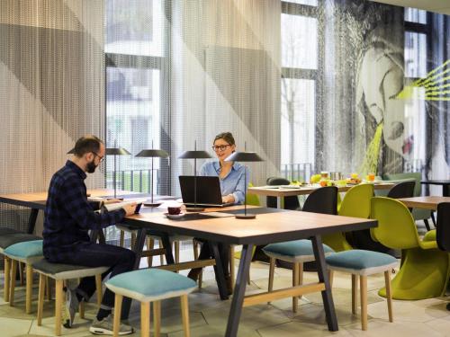 two people sitting at a table with a laptop at Aparthotel Adagio Köln City in Cologne