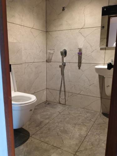 a bathroom with a shower with a toilet and a sink at TRIVPODS Capsule Hotel in Trivandrum