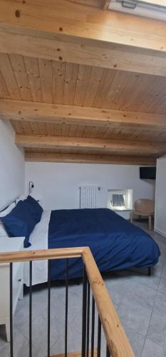 a bedroom with a bed with blue sheets and wooden ceilings at Casa Petelia in Serra San Bruno