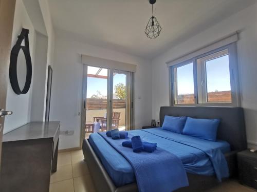 a bedroom with a bed with blue pillows on it at Sunny coast apartment by the sea in Protaras