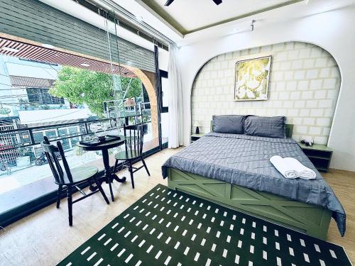 a bedroom with a bed and a balcony with a table at Mint Home in Danang