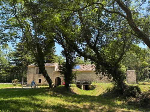 an old stone house with trees in the foreground at Le Moulin de Tiquetorte in Moulis-en-Médoc