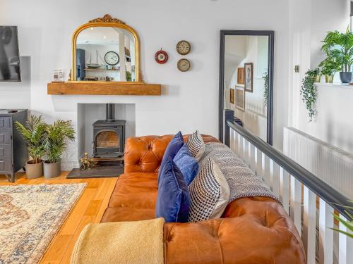 a brown leather couch in a living room with a mirror at Nautilus Cottage in Cellardyke