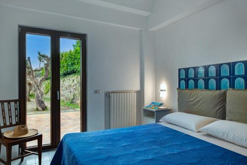 a bedroom with a blue bed and a sliding glass door at Villa Demetra Capri - Pool and Relaxation in Anacapri
