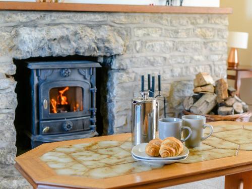 a table with croissants on a table with a fireplace at Rathlin Cottage in Cambridge
