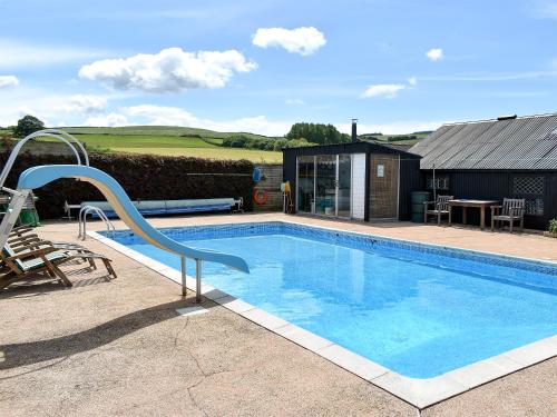 a swimming pool with a slide next to a house at Bournestream Cottage in Withycombe