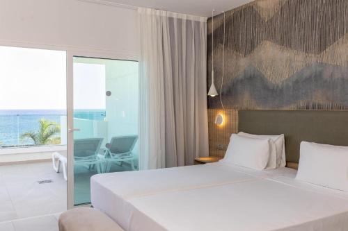 a bedroom with a large white bed and a balcony at Radisson Blu Resort, Lanzarote Adults Only in Costa Teguise