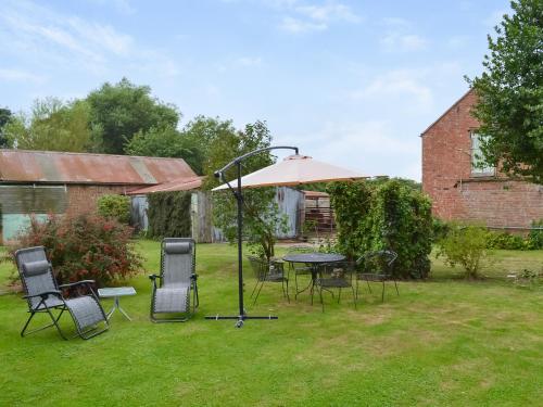 a table and chairs with an umbrella in a yard at Homestead in Long Sutton