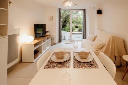 a white living room with a table and a couch at La Parenthèse - Appartement central avec terrasse in Pontarlier