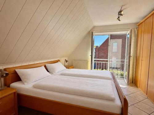 a bed in a room with a large window at Nordlicht in Krummhörn