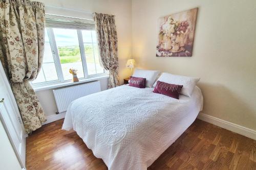 a bedroom with a white bed with two purple pillows at Hook Head Guest House in Fethard on Sea