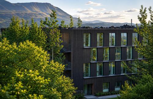 a building with trees and mountains in the background at Hótel Bifröst in Bifrost