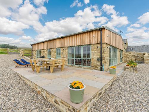 a stone building with a patio and a table and chairs at The Stables in Stanhope