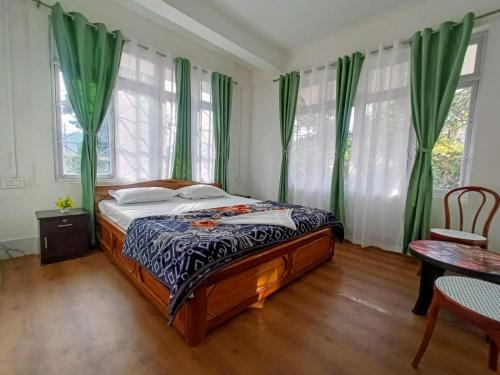 a bedroom with a bed with green curtains and a table at khim Retreat in Mirik