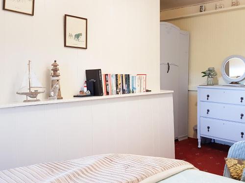 a bedroom with a bed and a shelf with books at Hendy in Llanfaelrhys