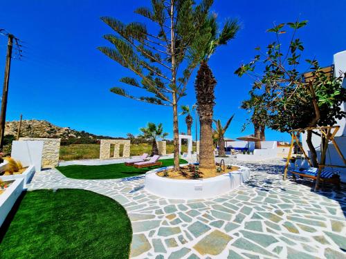 a patio with a palm tree and grass at Coralli Beach Apartments in Mikri Vigla