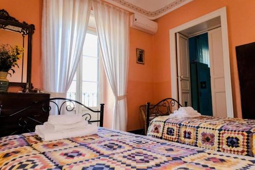 a bedroom with two beds and a window at Villa Castiglione 1863 - The real Sicilian holiday in Ragusa