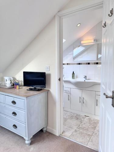 a kitchen with white cabinets and a desk with a sink at Broadlands View in Shaldon