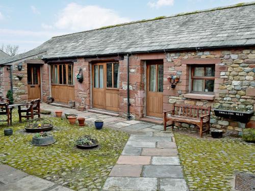 a stone cottage with a bench and a patio at Swallow's Nest - E3245 in Crackenthorpe