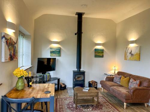 a living room with a couch and a wood stove at Blakeskerra Barn in Kenfig