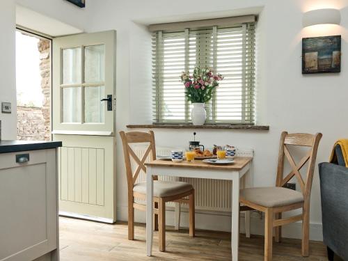 a kitchen with a table and chairs and a table and a window at Blakeskerra Barn in Kenfig