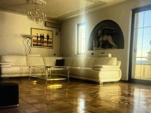 a living room with white furniture and a chandelier at Villa Maya in Portorož