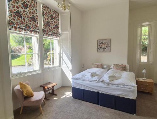 a bedroom with a bed and a chair and windows at Garden Flat- Private Luxury in Ashkirk
