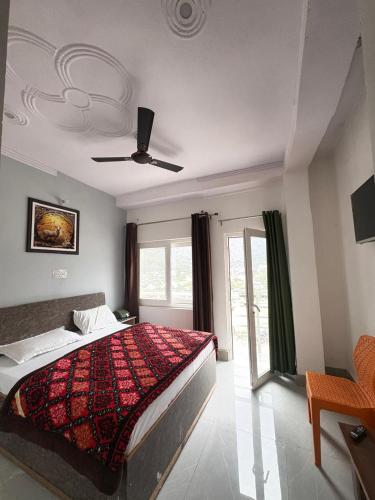 a bedroom with a bed with a red comforter at Hotel Ganpati place in Uttarkāshi