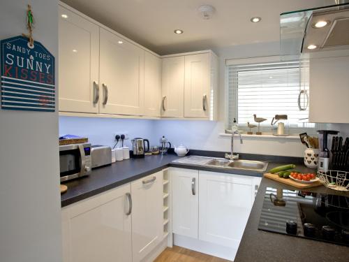 a kitchen with white cabinets and a sink at Dunlin 1 - The Cove in Brixham