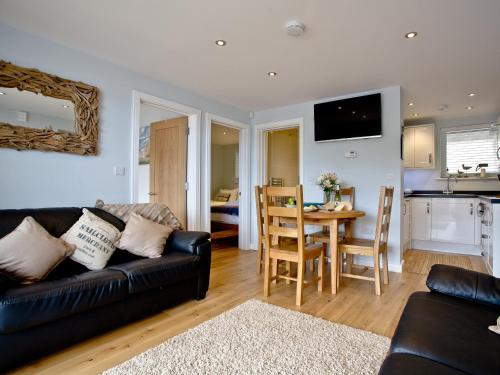 a living room with a black couch and a table at Dunlin 1 - The Cove in Brixham