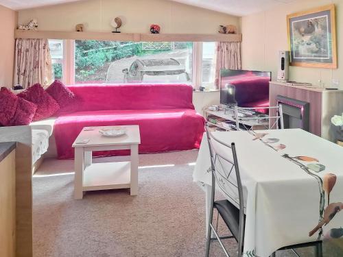 a living room with a pink couch and a table at Glen Y Nant in Llanfihangel-nant-Melan