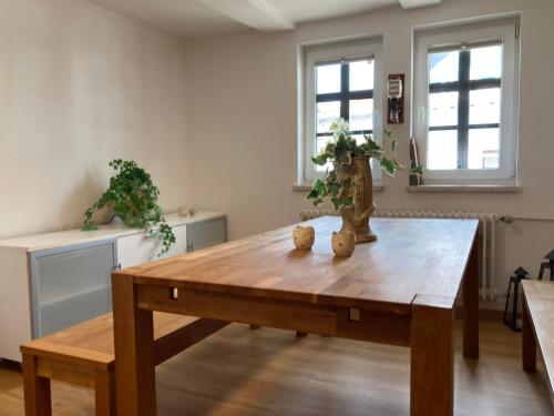 a wooden table in a living room with two windows at Ferienwohnung Lukas in Frielendorf