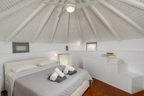 a bedroom with a white bed with a white ceiling at WindMilos in Tripiti