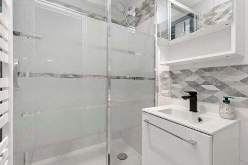 a white bathroom with a shower and a sink at Maisonnette de la mer Batz sur mer in Batz-sur-Mer