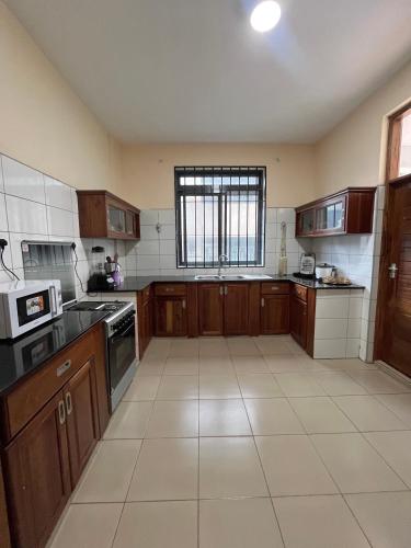 a large kitchen with wooden cabinets and a window at QD Apartment Simba Unit in Arusha