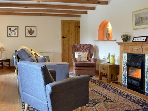 a living room with two chairs and a fireplace at The Paddock in Saint Hilary