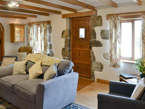 a living room with a couch and a stone wall at The Paddock in Saint Hilary
