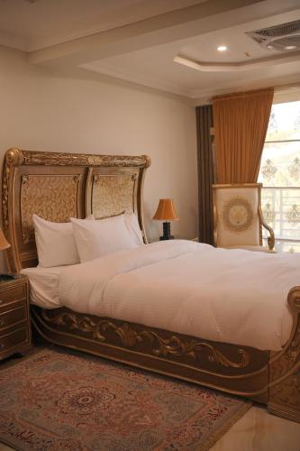 a bedroom with a large bed with white sheets and a window at Burj A Zafar in Murree