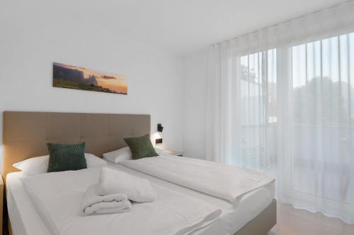 a white bed with two towels on it in a bedroom at Bike Apartments Curti - Waldgrün in Laives