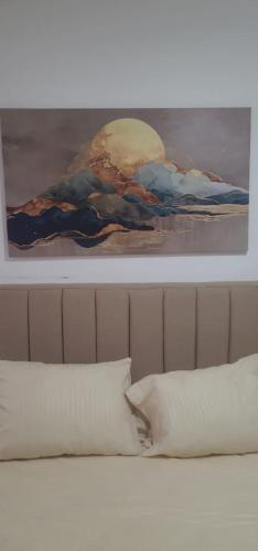 a painting above a bed with a white pillow at CoCo Nest Cozy Modern Studio Near Mamsha Beach & Airport in Hurghada