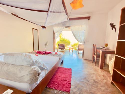 a bedroom with two beds and a table and a red rug at Ampasoa Beach in Nosy Be