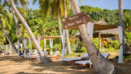 a bunch of chairs and a sign on a beach at Ampasoa Beach in Nosy Be
