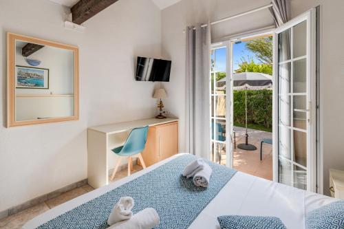 a bedroom with a bed and a desk and a balcony at Hôtel La Nartelle in Sainte-Maxime
