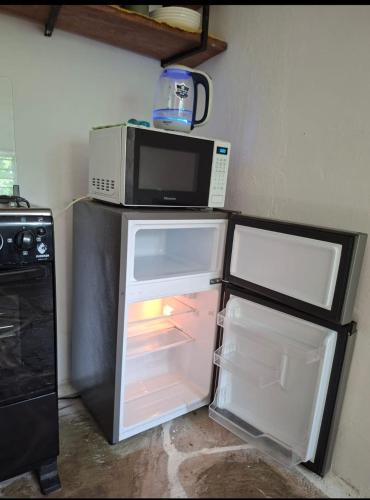 an open refrigerator with a microwave on top of it at The Nook,Kilifi in Kilifi