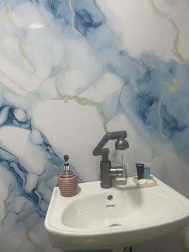 a bathroom with a sink with clouds on the wall at Guest house River side in Adishi
