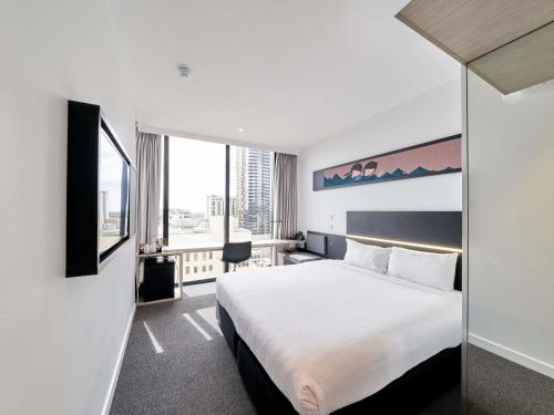 a hotel room with a bed and a large window at ibis Adelaide in Adelaide