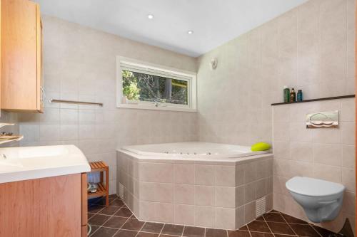 a bathroom with a tub and a toilet and a window at Skyline View - Nordic Villa Above Bergen in Bergen