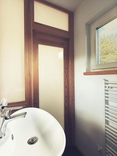 a bathroom with a white sink and a window at Nowy dom przy starym krześle - w Pelniku in Pelnik