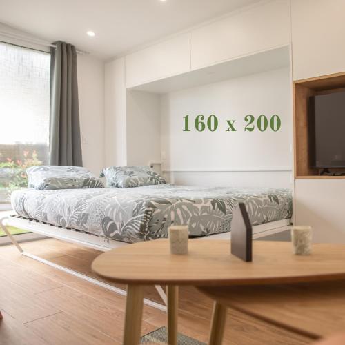 a bedroom with a bed and a table and a tv at Rez de Jardin - Calme & Familiale in Varreddes